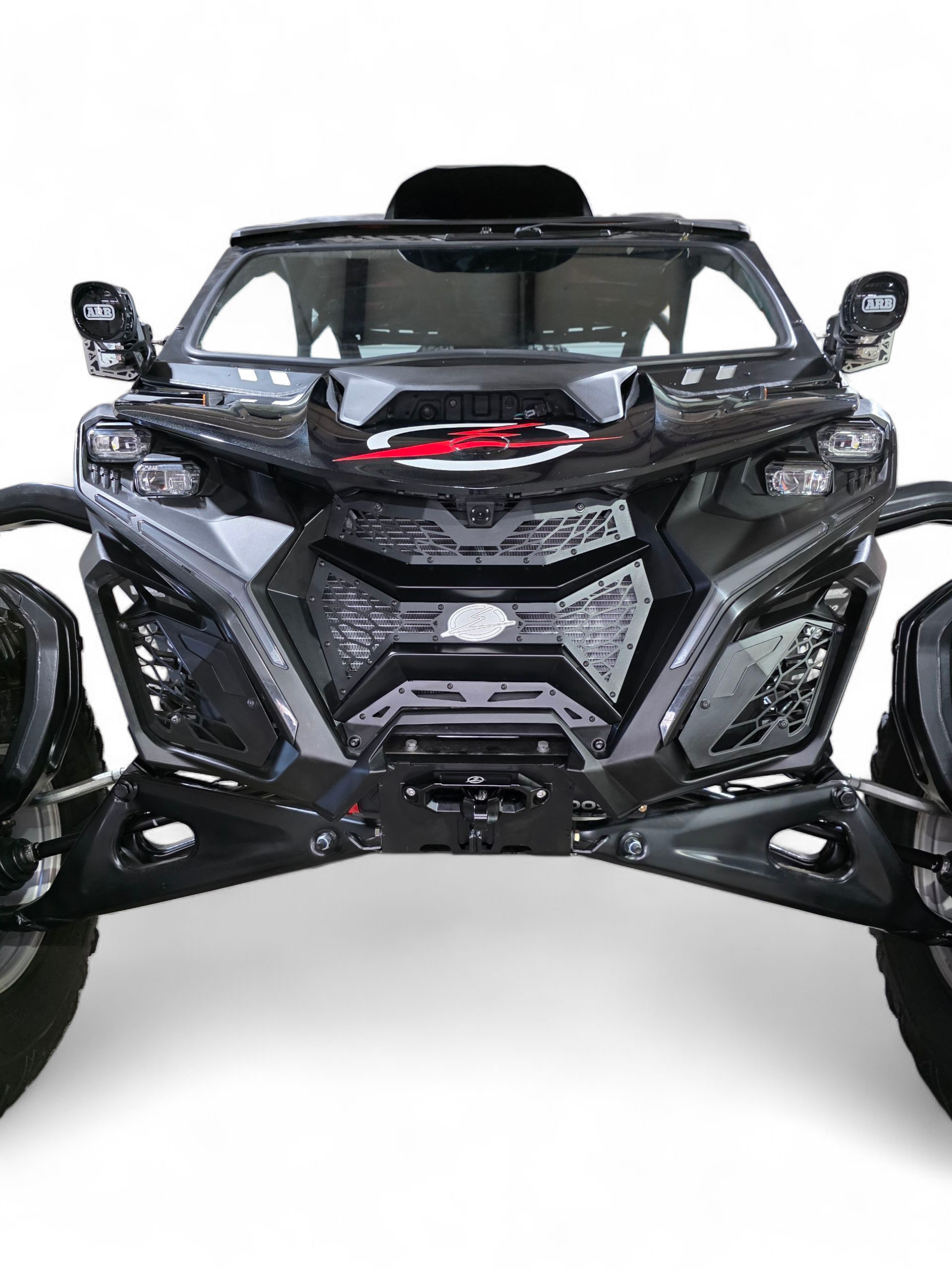 2024 Can-Am Maverick R fitted with Volt 3-Piece Grille in hammer black powder coat
finish, full front view on a desert trail showing contour-matched fitment and
billet aluminum badge detail
