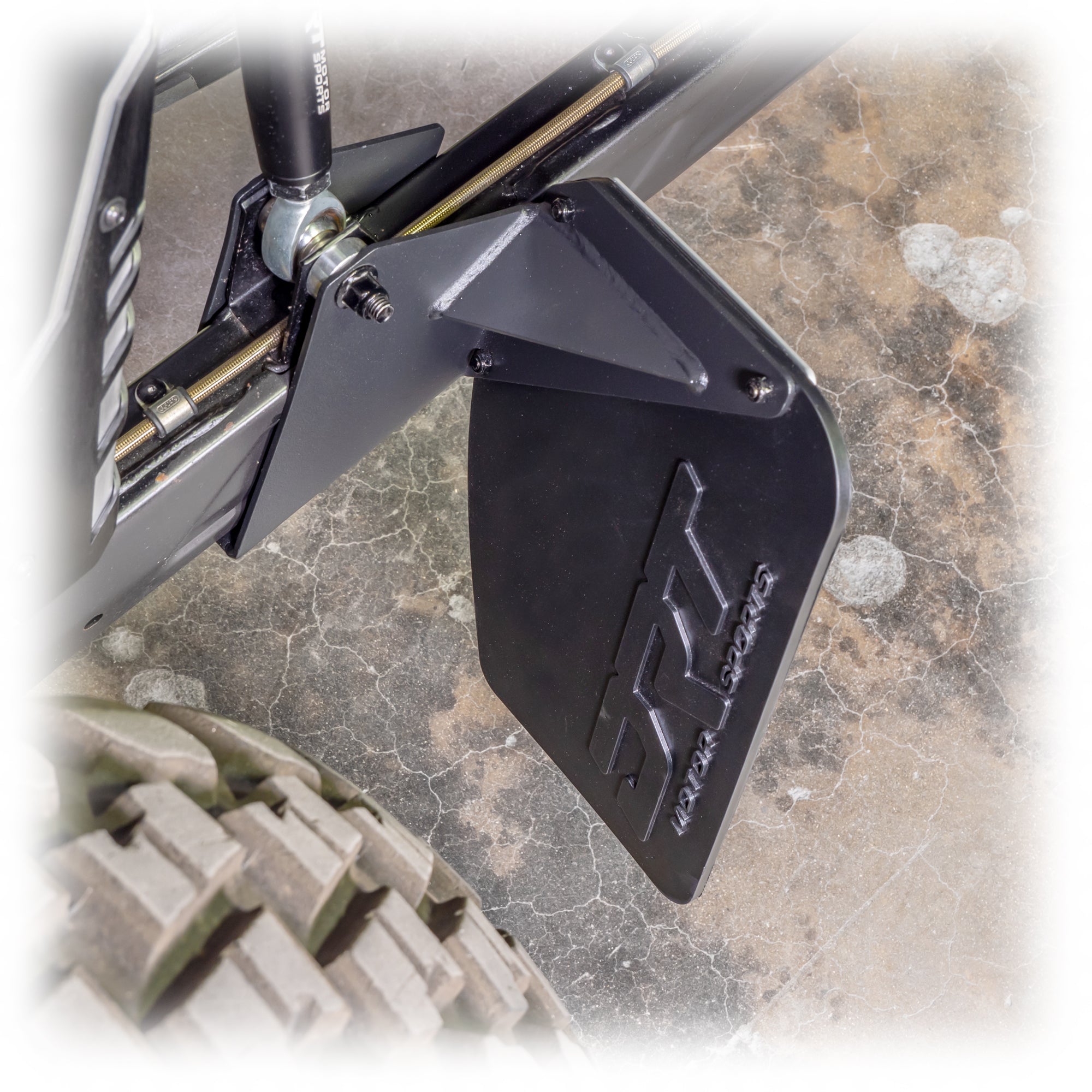 Rock guard protecting CV boots and brake calipers on UTV rear suspension