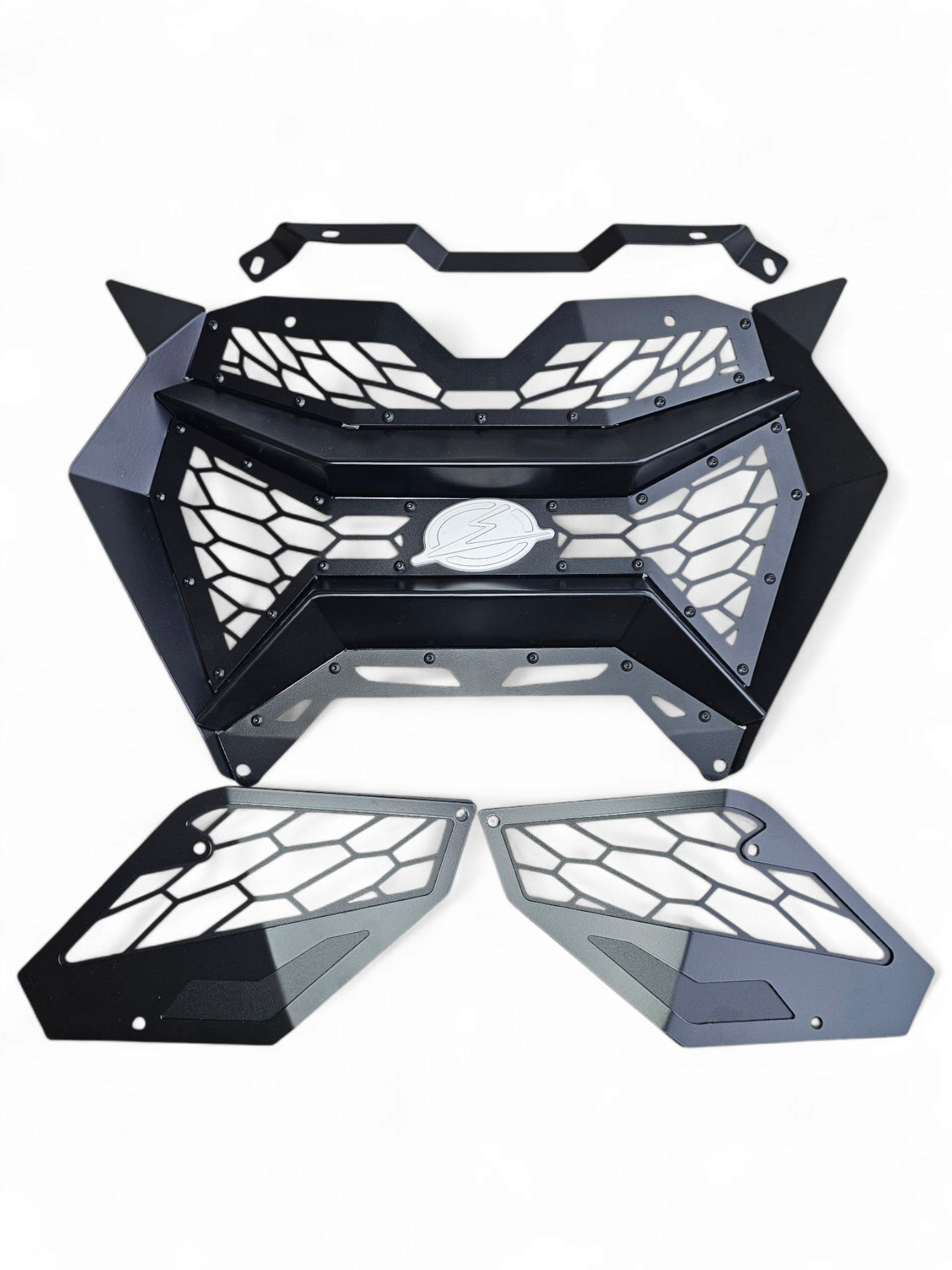 Volt 3-Piece Grille unboxed beside 2024 Can-Am Maverick R showing three grille
    sections, billet badge, and complete bolt-in hardware kit