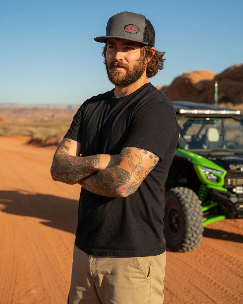 Man wearing the EOD Charcoal Two-Tone Trucker Hat outdoors next to a UTV on the trail